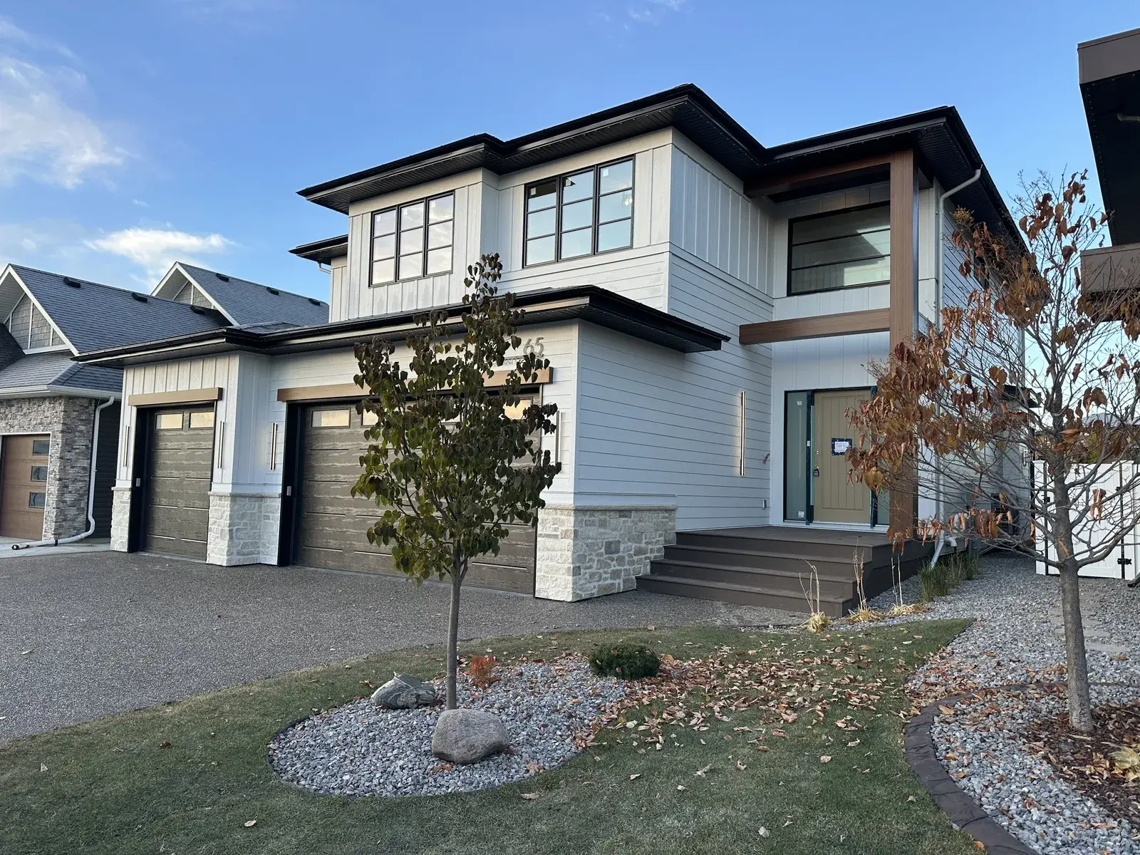 Completed two-storey exterior in the Red Deer area — light board-and-batten and lap siding with cedar-look accents and stone, finished by PJM Home Advantage